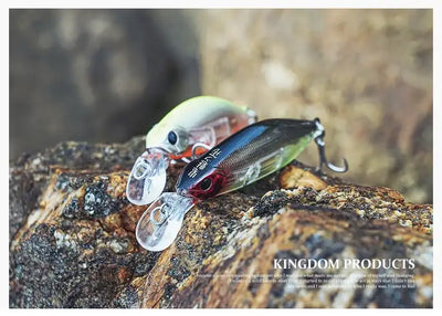 Sinking minnow fishing lures with silver, black, and green accents on rocky surface