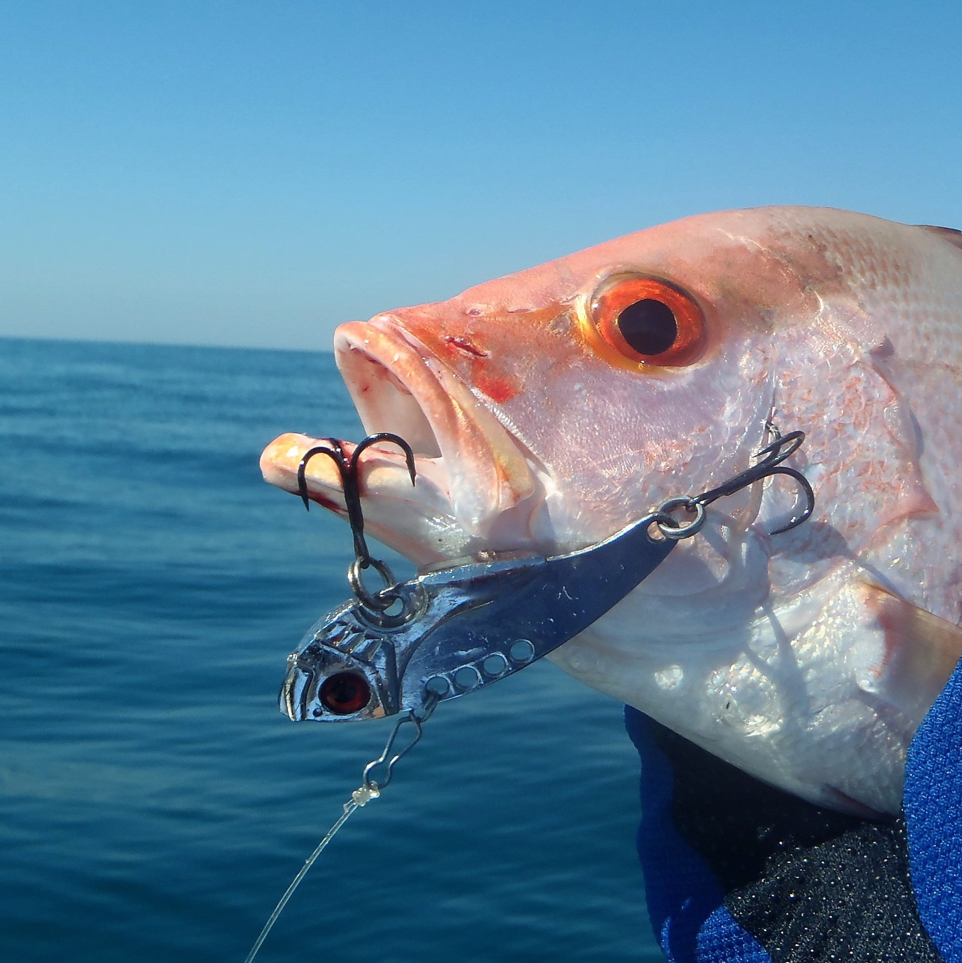 Fishing lure with chrome/silver body and red eye, shown with treble hooks and chain
