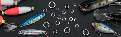 Assorted silver fishing split rings scattered among fishing lures and hardware