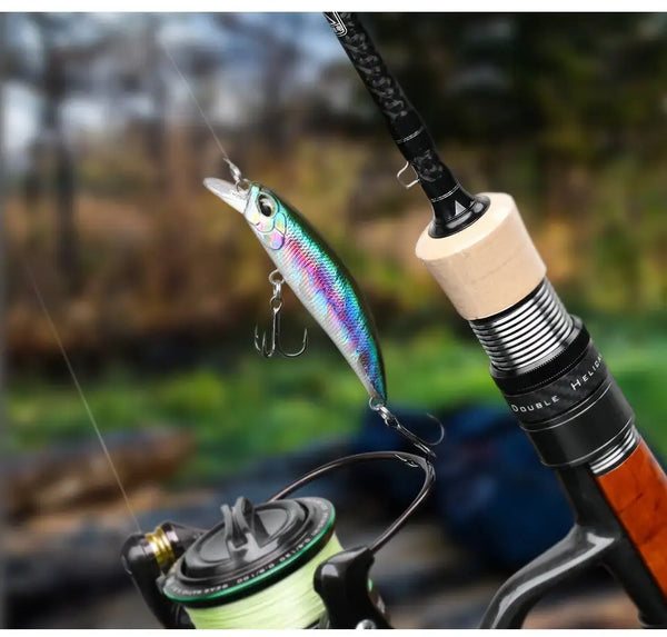 Holographic rainbow sinking minnow crankbait with treble hooks near a fishing rod