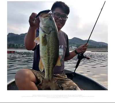 Metallic silver-green swimbait lure with treble hooks held beside a fish catch.