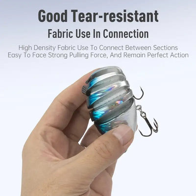 Hand holding a multi-jointed hard fishing lure, silver-blue body, treble hooks
