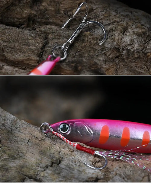 Pink and purple metal fishing jig lure with orange accents and double hook on rock
