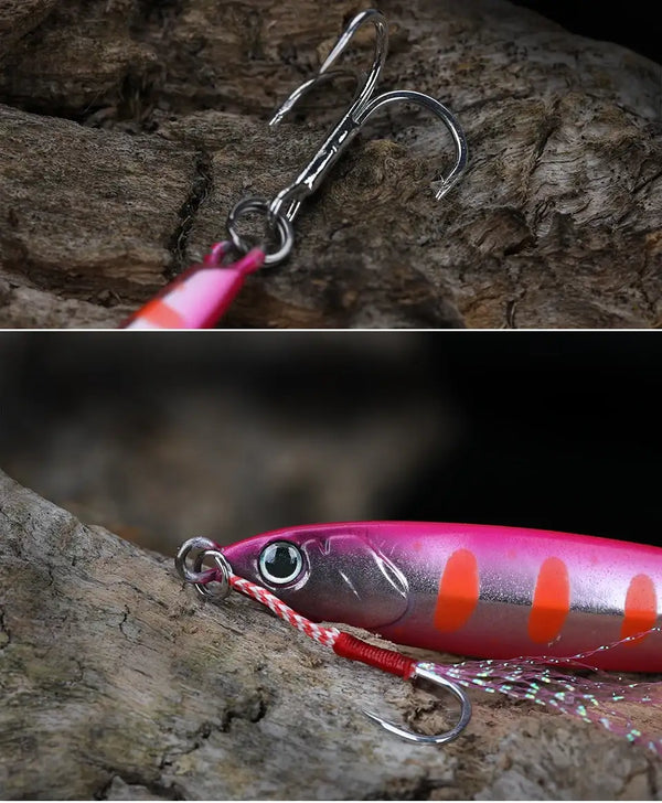 Pink and purple metal fishing jig lure with orange accents and double hook on rock