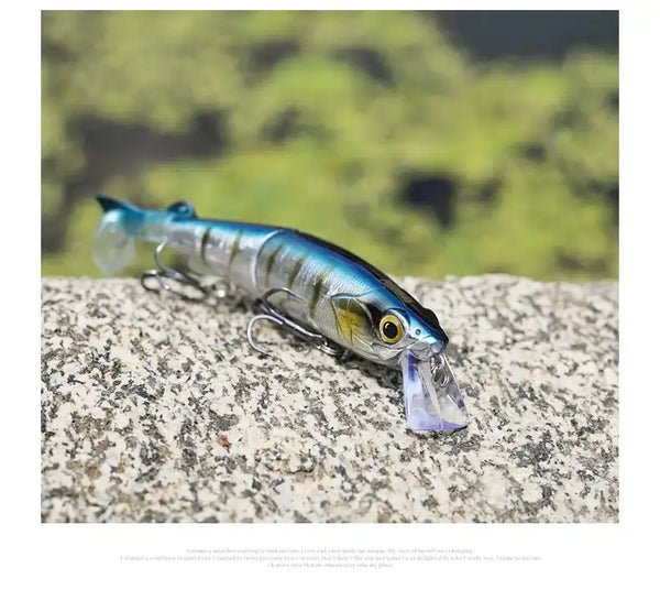 Blue and silver multi-jointed minnow surface fishing lure on rock
