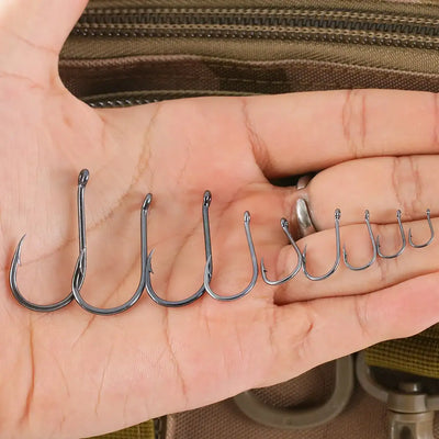 Offset fishing hooks lined up in palm, dark steel, barbed points