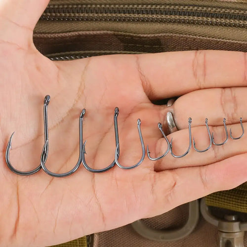 Offset fishing hooks lined up in palm, dark steel, barbed points