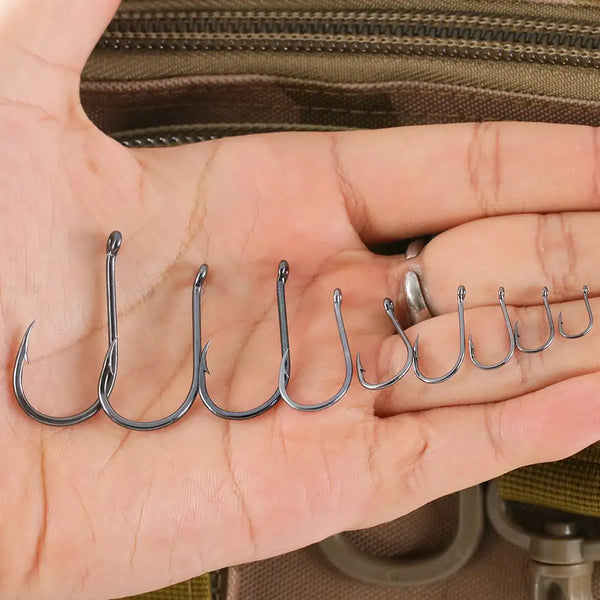 Offset fishing hooks lined up in palm, dark steel, barbed points