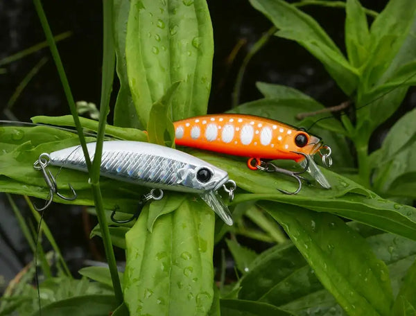 Sinking minnow fishing lure with orange head, silver body, and red treble hooks