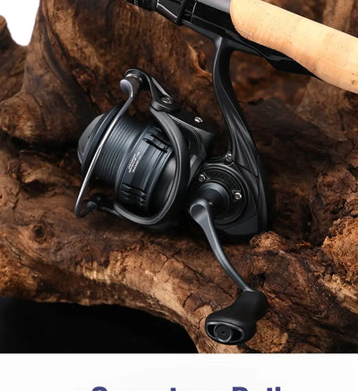 Black spinning fishing reel with crank handle and ridged spool, resting on rock