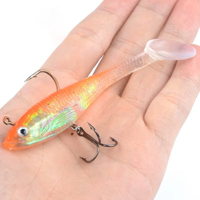 Luminous orange fishing lure with treble hooks, held on an open palm