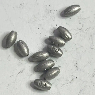 Fishing lead slip sinkers, dark gray oval weights scattered on a light surface
