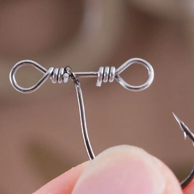 Drop shot swivel hook held between fingers, showing two rings and spring coil