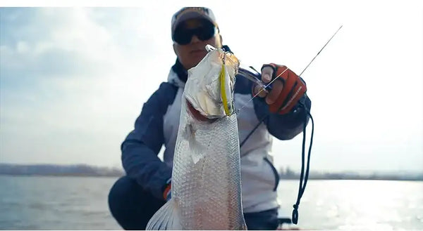 Fishing catch with lure and treble hook held up on a boat