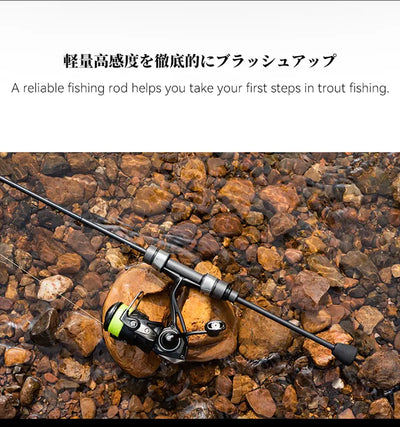Spinning fishing rod with reel lying on rocky riverbed, set up for trout
