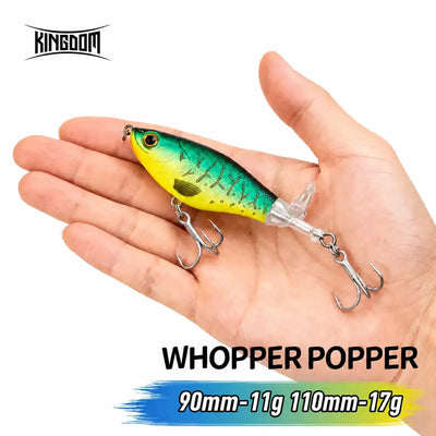 Artificial popper fishing lure, teal and chartreuse body with treble hooks, in hand