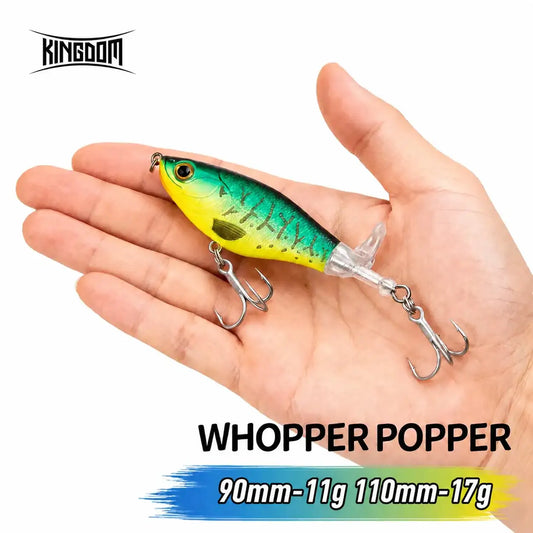 Artificial popper fishing lure, teal and chartreuse body with treble hooks, in hand