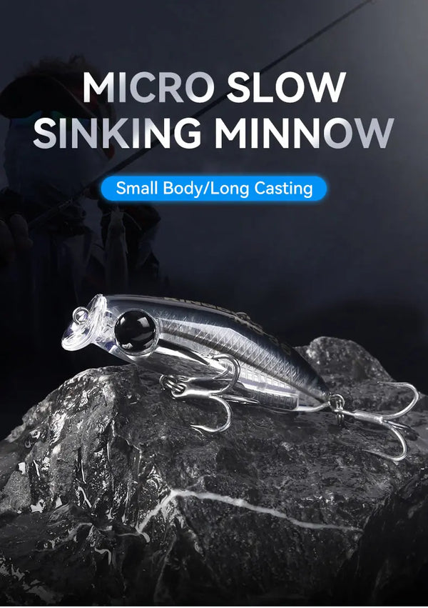 Micro slow-sinking minnow fishing lure with black eye and treble hooks on rocks