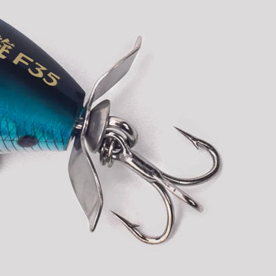 Close-up of topwater wobbler lure with chrome treble hooks and blue-green body