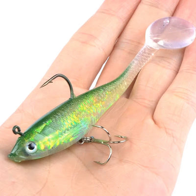 Luminous green fishing lure with treble hooks, held on an open palm