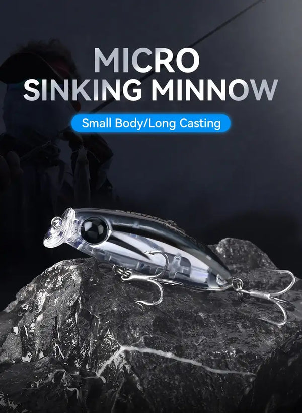 Silver micro minnow lure with black eye and treble hooks on rocky surface