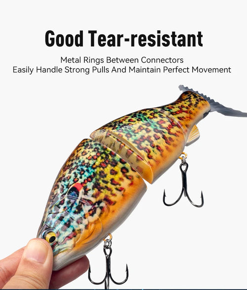 Orange-speckled jointed fishing swimbait with three treble hooks, close-up hand