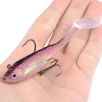 Luminous pink/purple fishing lure with treble hooks, held on an open palm