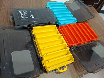 Assorted double-sided tackle boxes open with gray, blue, yellow, and orange inserts