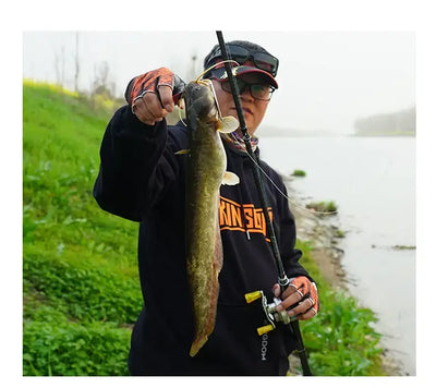 Orange half-finger fishing gloves on hands while holding a fishing rod