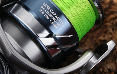 Neon green braided fishing line close-up on a metallic reel spool