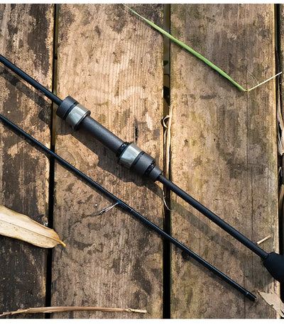 Light game fishing rod with guide rings and EVA handle, laid on weathered wood