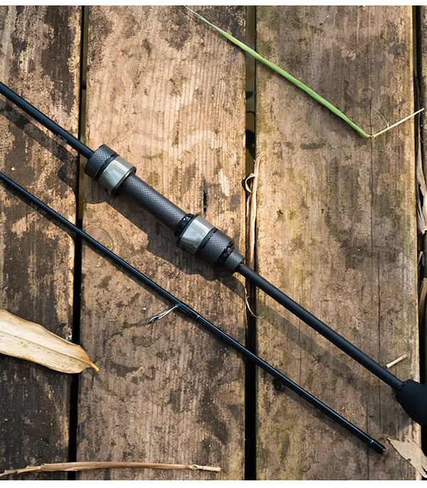 Light game fishing rod with guide rings and EVA handle, laid on weathered wood
