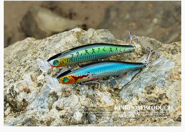 Two floating minnow lures with treble hooks on rocky shore