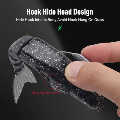 Black speckled swimbait lure with hook hidden under head cover, gray tail fin.