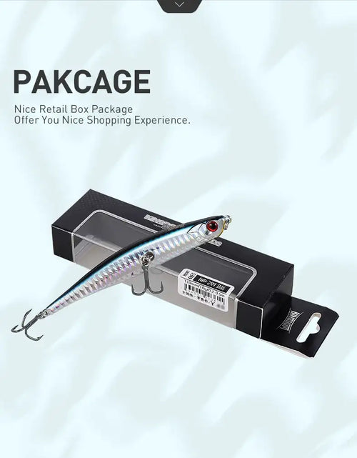 Floating pencil jerkbait lure in clear box packaging, silver-blue body and treble hooks.