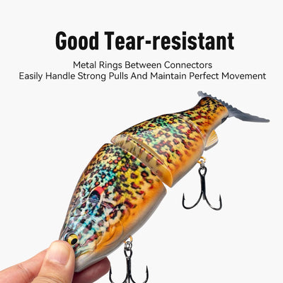 Orange-speckled jointed fishing swimbait held in hand with treble hooks