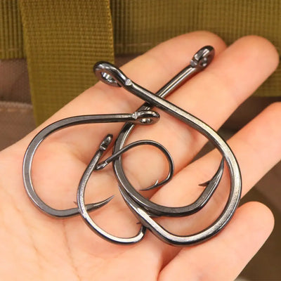 Set of curved black live bait hooks resting in a hand