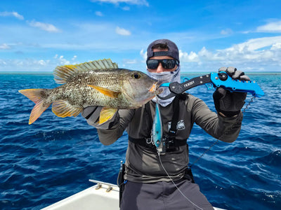 Angler on a boat holding a fish with a blue Noeby fish lip grip