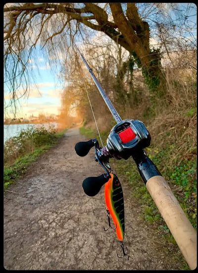Fishing rod in hand with spinning reel near a riverside path
