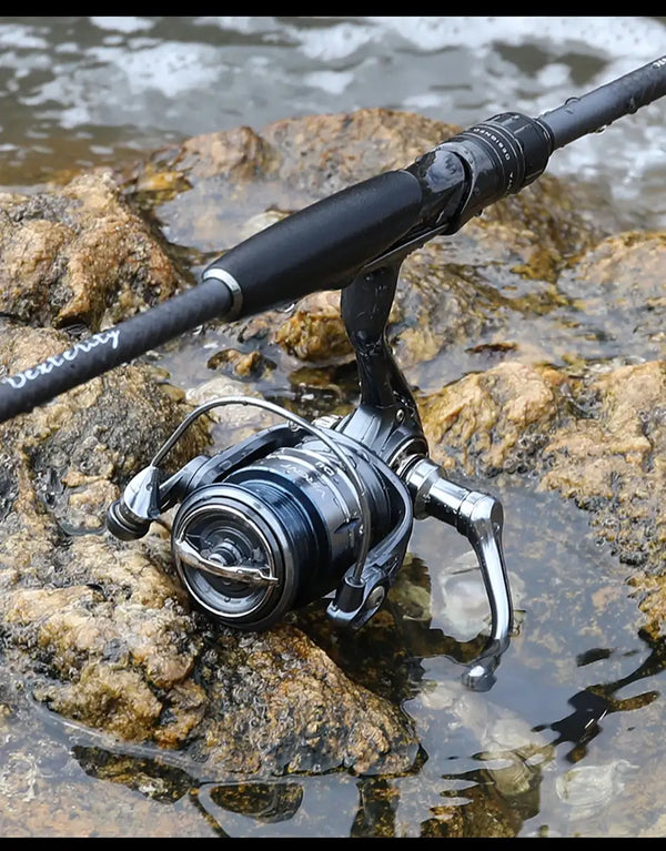 Tsurinoya long-cast spinning reel on rocks, silver spool and black handle