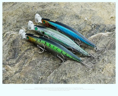 Floating minnow lures on rocks, teal-blue and green bodies with clear lips and treble hooks