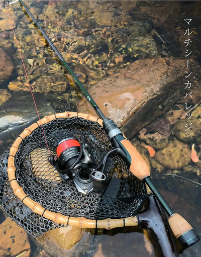 Spinning reel with green fishing line on a rod, resting on a rock-lined net