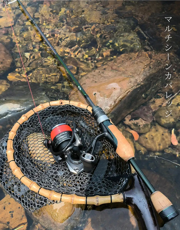 Spinning reel with green fishing line on a rod, resting on a rock-lined net