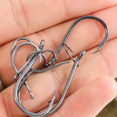 Assorted offset fishing hooks with barbs, dark metal finish, shown in hand
