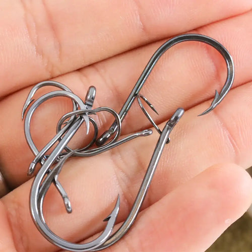 Assorted offset fishing hooks with barbs, dark metal finish, shown in hand
