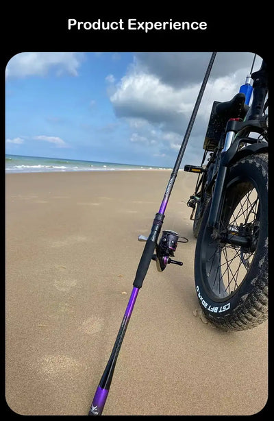 Casting fishing rod with purple shaft and reel, held on sandy beach