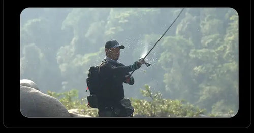 Ultralight fishing rod held by angler near water, dark silhouette with green accent