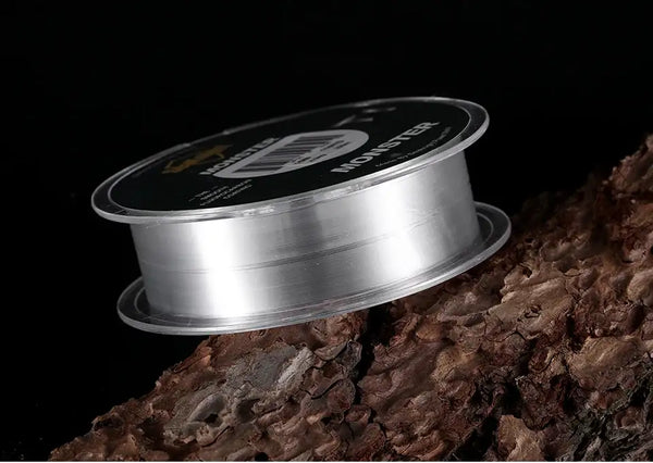 Fishing line spool in profile with MANSTER T1 label and clear line on rocky surface