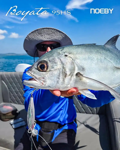 Angler holding a silvery fish beside a “Broyata 95HS” lure