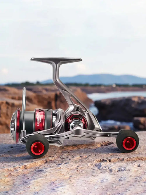Spinning fishing reel with silver body, black grips, and red handle caps